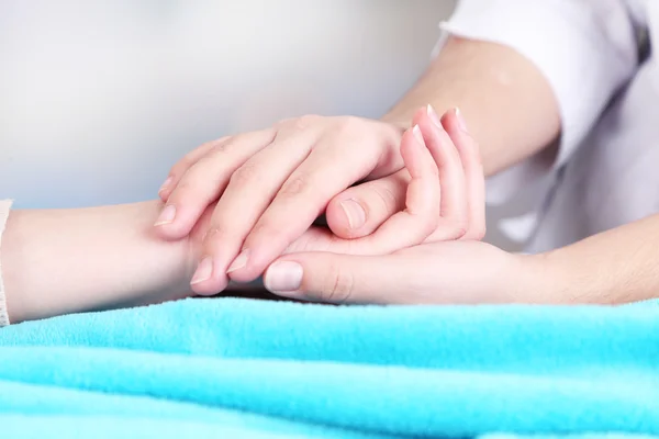 Medical doctor holding hand of patient, on light background — Stock Photo, Image