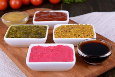 Various sauces on chopping board on table close-up clipart