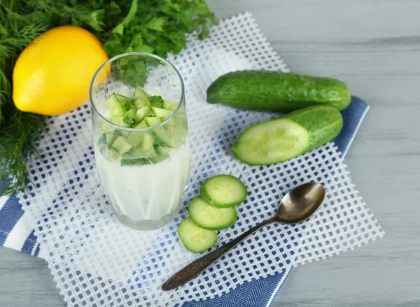 Cucumber yogurt in glass, on color napkin, on wooden background — Stock Photo, Image