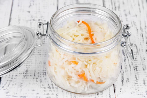 Marinated cabbage (sauerkraut) in glass jar, on wooden background — Stock Photo, Image