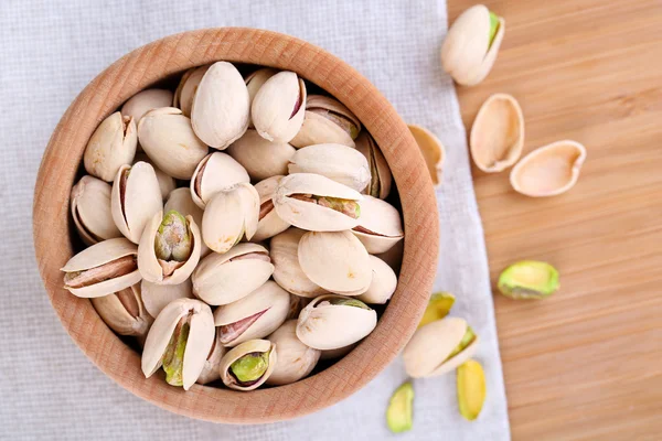 Pistaches dans un bol en bois sur fond de tissu — Photo