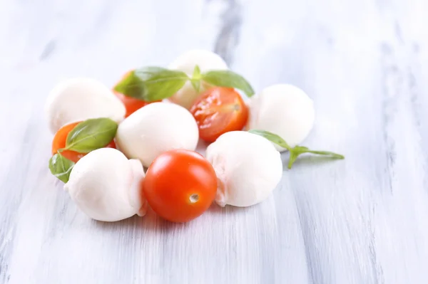 Smakelijke mozzarella kaas met basilicum en tomaten, op houten tafel — Stockfoto