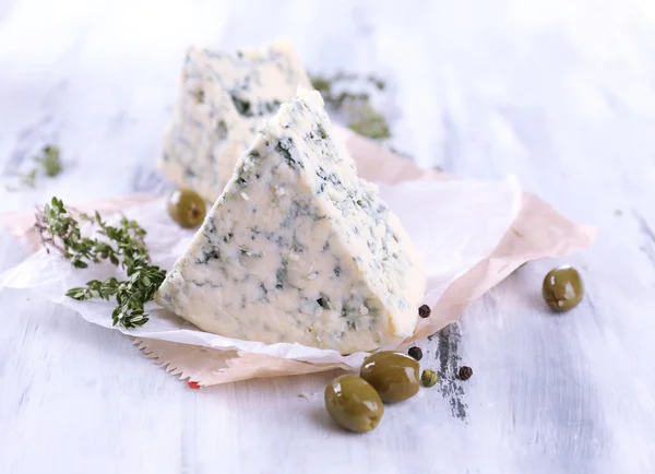 Smakelijke blauwe kaas met tijm en olijven op houten tafel — Stockfoto