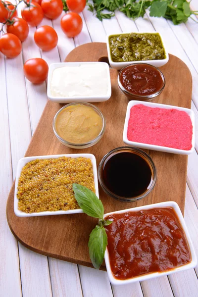 Различные соусы на разделочной доске на столе крупным планом — стоковое фото