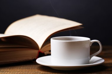 sıcak kahve ile masaya koyu arka plan üzerinde kitap