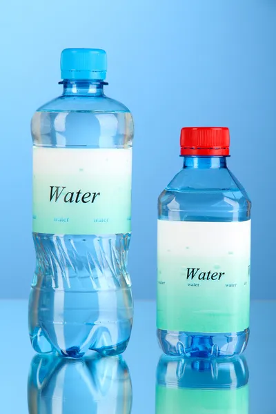 Τα διαφορετικά την μπουκάλια νερό με ετικέτα σε μπλε φόντο — Φωτογραφία Αρχείου