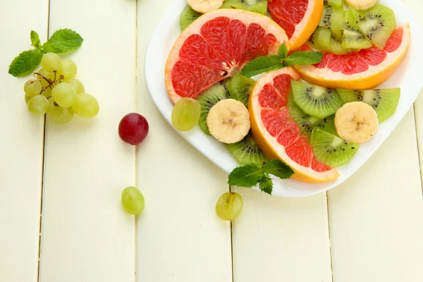 Sortiment von geschnittenen Früchten auf Teller, auf weißem Holztisch — Stockfoto