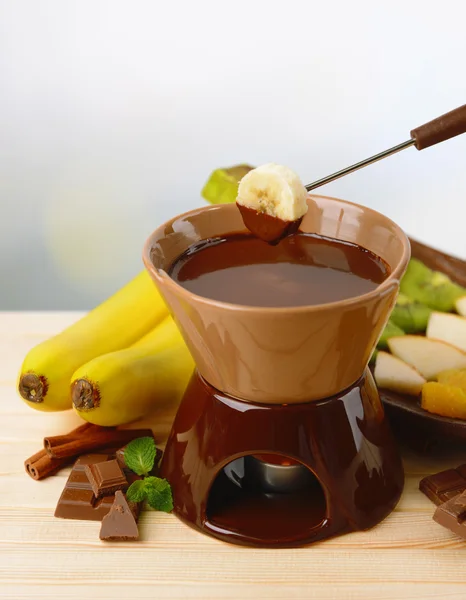 Fondue σοκολάτας με φρούτα, στο ξύλινο τραπέζι, επάνω ελαφρύς υπόβαθρο — Φωτογραφία Αρχείου