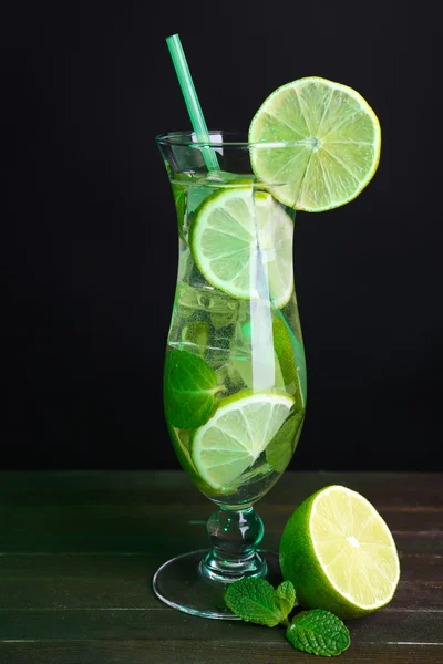 Glass of cocktail with lime and mint on table on black background — Stock Photo, Image
