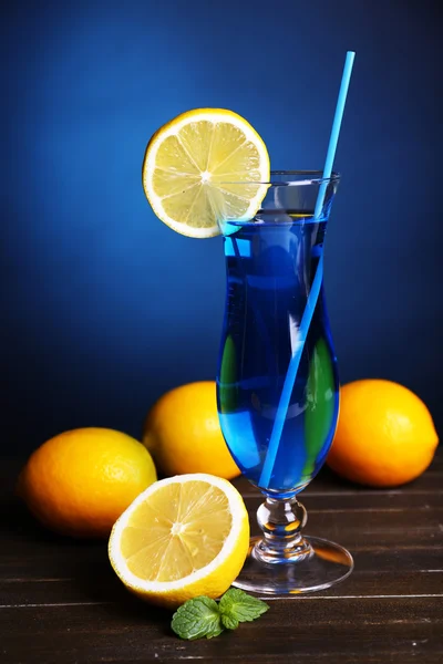 Glass of cocktail on table on dark blue background — Stock Photo, Image