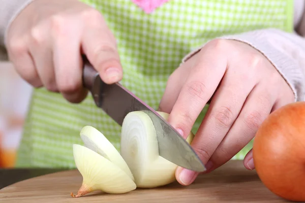 Female hands cutting bulb onion, on kitchen background — Stock Photo, Image