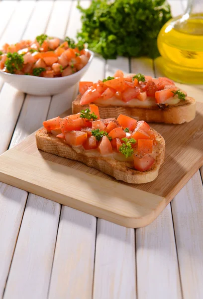 Delicious bruschetta with tomatoes on cutting board close-up — Stock Photo, Image