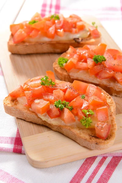 Deliciosa bruschetta con tomates en la tabla de cortar de cerca —  Fotos de Stock