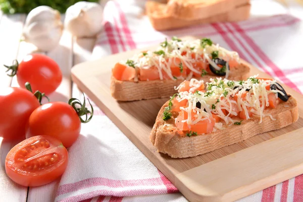 Deliciosa bruschetta con tomates en la tabla de cortar de cerca —  Fotos de Stock