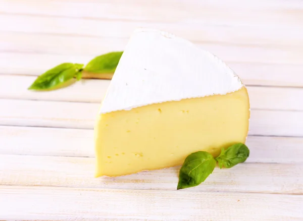 Tasty Camembert cheese with basil, on wooden table — Stock Photo, Image