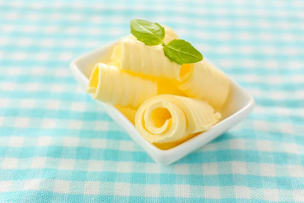 Kadeře čerstvého másla s bazalkou v míse, na modrý ubrus — Stock fotografie