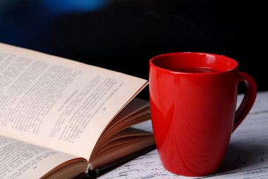 Tablodaki koyu arka plan üzerinde kitapla sıcak çay