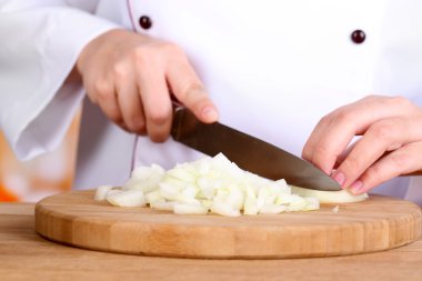 Mutfak arka planında soğan doğrayan kadın elleri.