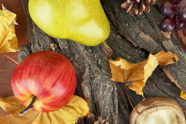 Fruits with mushroom and yellow leaves on wooden background — Stock Photo, Image