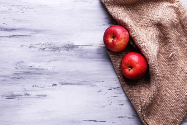 Äpfel und Sacktuch auf Holzgrund — Stockfoto