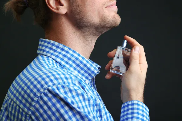 Schöner junger Mann mit Parfüm auf schwarzem Hintergrund — Stockfoto