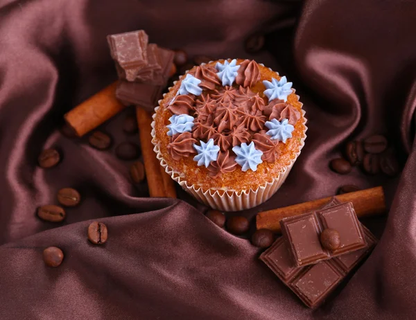 Välsmakande cupcake med smörkräm, på färg tyg bakgrund — Stockfoto