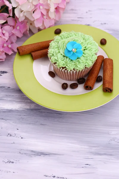 Smakelijke cupcake met boter room, op de plaat, op een houten achtergrond kleur — Stockfoto