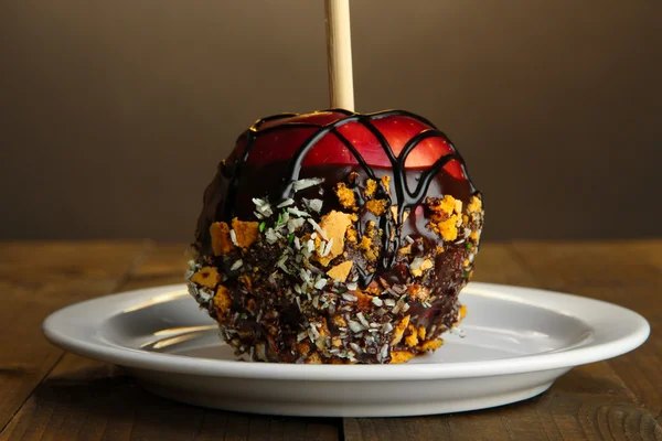 Candied apple on stick on wooden table — Stock Photo, Image