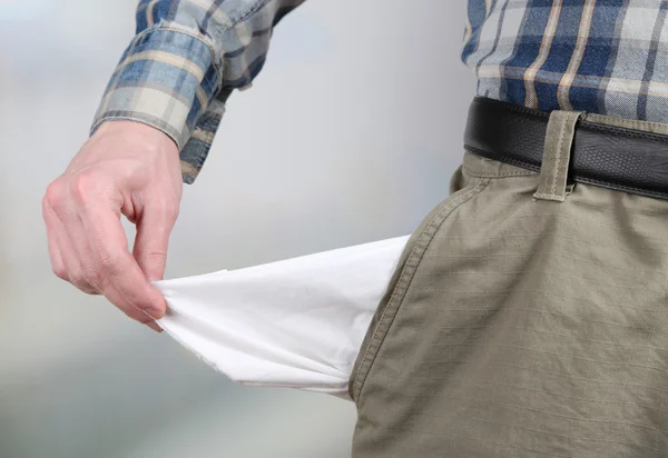 Hombre mostrando su bolsillo vacío sobre fondo brillante —  Fotos de Stock