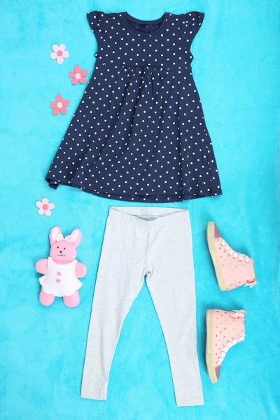 Beautiful clothes for little girl on blue background — Stock Photo, Image