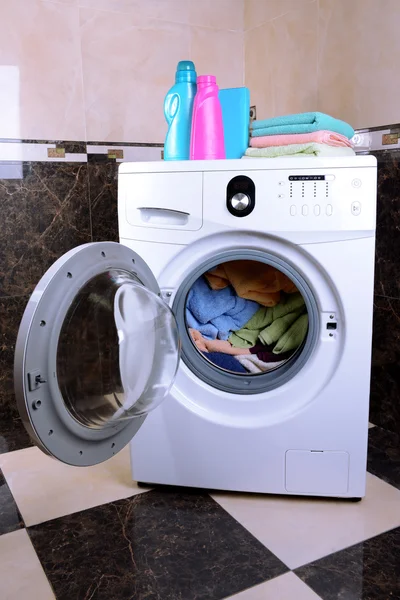 Wasmachine geladen met kleding in badkamer — Stockfoto