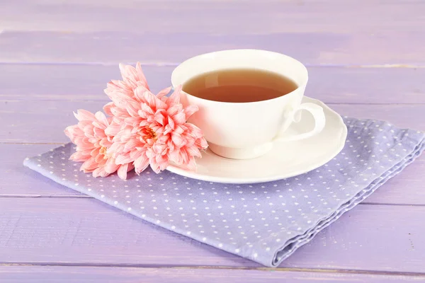Růžové chryzantémy a šálek čaje na dřevěný stůl — Stock fotografie