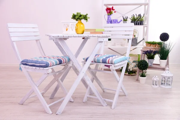 Chaises de jardin et table avec des fleurs sur des étagères sur fond blanc — Photo