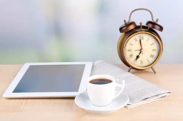 Tableta, periódico, taza de café y despertador en mesa de madera — Foto de Stock