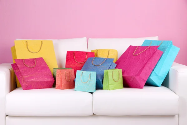 Sacos de compras coloridos no sofá, no fundo da parede de cor — Fotografia de Stock
