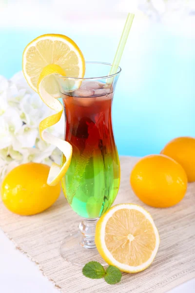 Glass of cocktail on table on light blue background — Stock Photo, Image