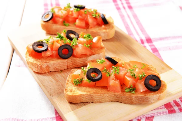 Delicious bruschetta with tomatoes on cutting board close-up — Stock Photo, Image