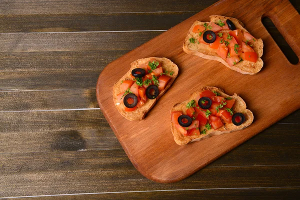 Deliciosa bruschetta con tomates en la tabla de cortar de cerca —  Fotos de Stock