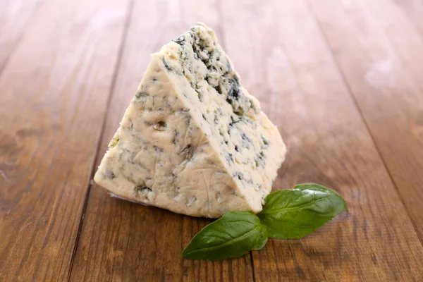 Gustoso formaggio blu con basilico, su tavola di legno — Foto Stock