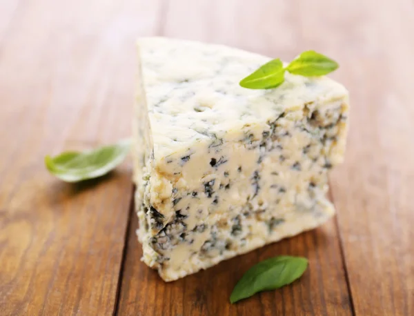Tasty blue cheese with basil, on wooden table — Stock Photo, Image