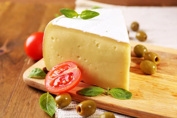 Вкусный сыр Камамбер с помидорами, оливками и базиликом, на деревянном столе — стоковое фото