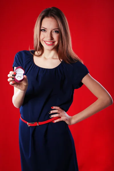 Girl looks at box with wedding ring on color background — Stock Photo, Image