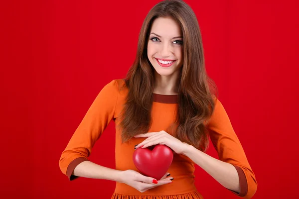 Mulher atraente com coração, no fundo vermelho — Fotografia de Stock