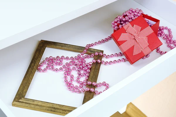 Gift box and beads in open desk drawer close up — Stock Photo, Image