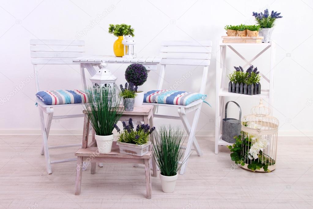 Garden chairs and table with flowers on wooden stands on white background