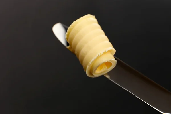 Curl of fresh butter on knife on grey background — Stock Photo, Image