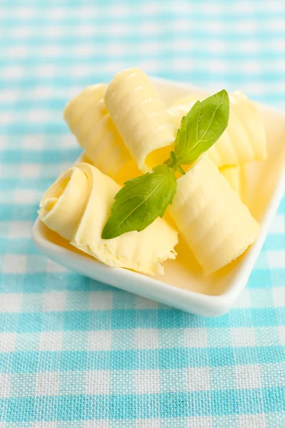 Locken frischer Butter mit Basilikum in Schüssel, auf blauer Tischdecke — Stockfoto