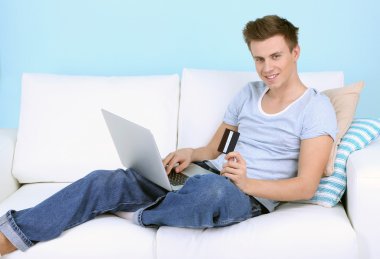 kanepe adam yalanla mavi arka plan üstünde laptop