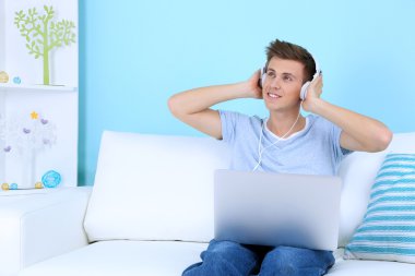 adam kanepede oturan ve üzerinde mavi arka plan müzik dinlemek