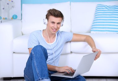 adam yere oturmak ve Oda arka planda müzik dinlemek
